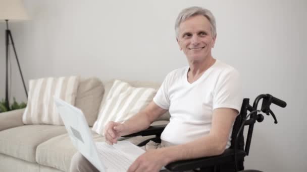 Hombre discapacitado en silla de ruedas usando portátil en el hospital — Vídeos de Stock