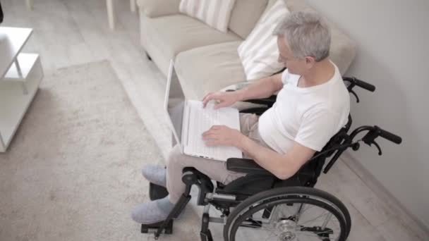 Homem com deficiência em uma cadeira de rodas digitando no laptop — Vídeo de Stock