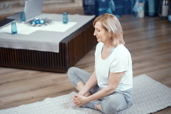 Una donna di età superiore ai 50 anni sta facendo yoga a casa . — Foto Stock