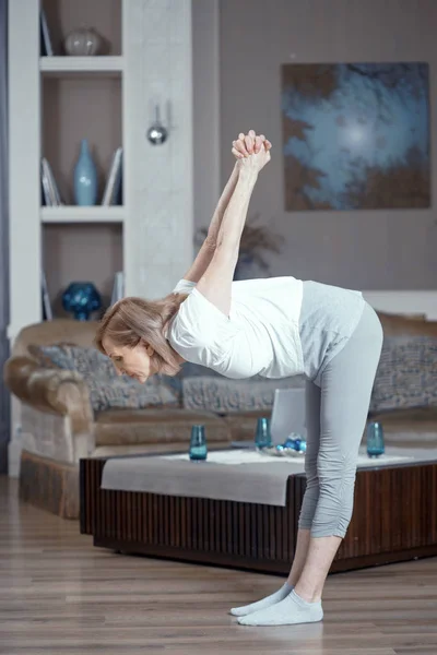 50-летняя старуха практикует йогу дома в гостиной . — стоковое фото
