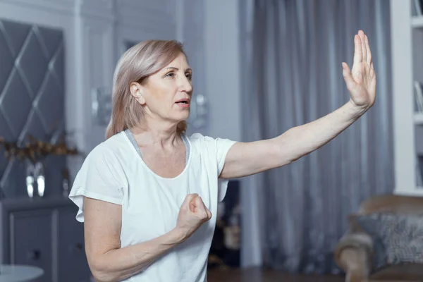 Uma mulher de 50 anos pratica Yoga em casa na sala de estar . — Fotografia de Stock