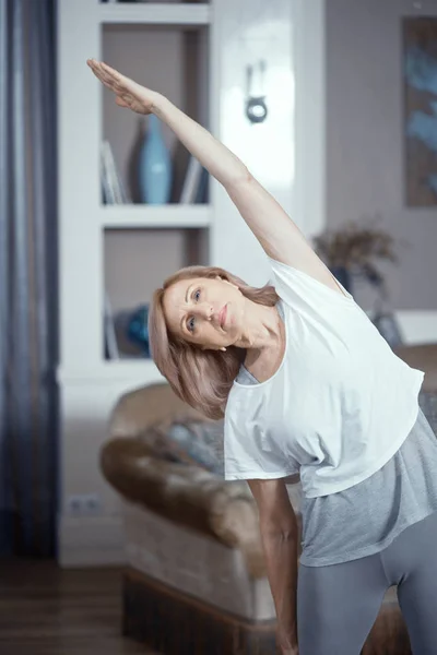 Femeia de vârstă mijlocie face yoga acasă — Fotografie, imagine de stoc