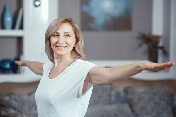 Uma mulher de 50 anos pratica Yoga em casa na sala de estar . — Fotografia de Stock