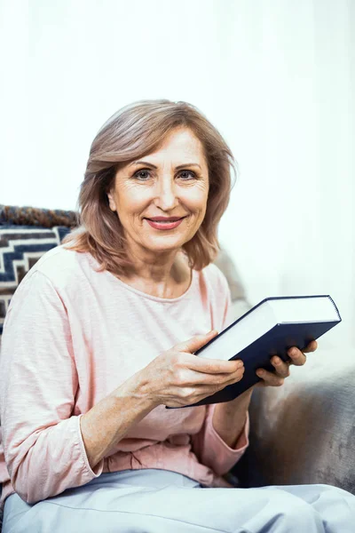 Mulher idosa com um livro azul grosso em suas mãos . — Fotografia de Stock