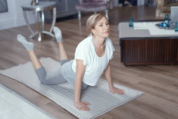 Mujer de mediana edad haciendo ejercicio de yoga en la estera — Foto de Stock