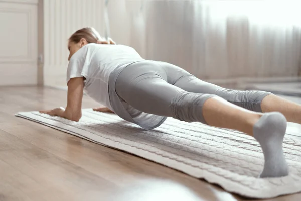 Mulher de meia-idade fazendo posição prancha de ioga no tapete — Fotografia de Stock