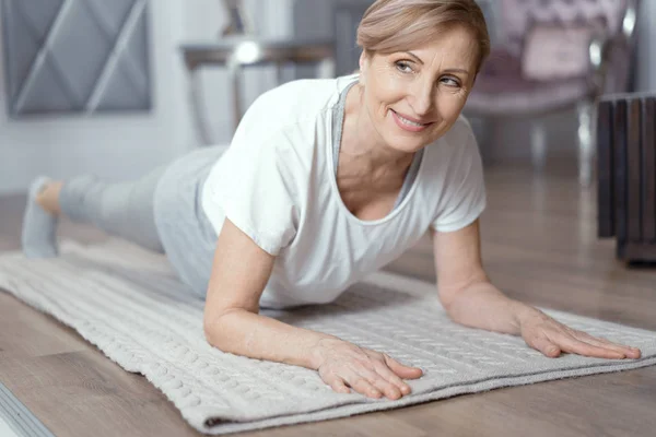 Mujer de mediana edad haciendo posición de tablón de yoga en la estera — Foto de Stock