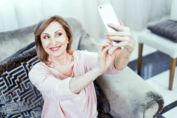 Beautiful middle aged woman in casual clothes is making selfie — Stock Photo, Image