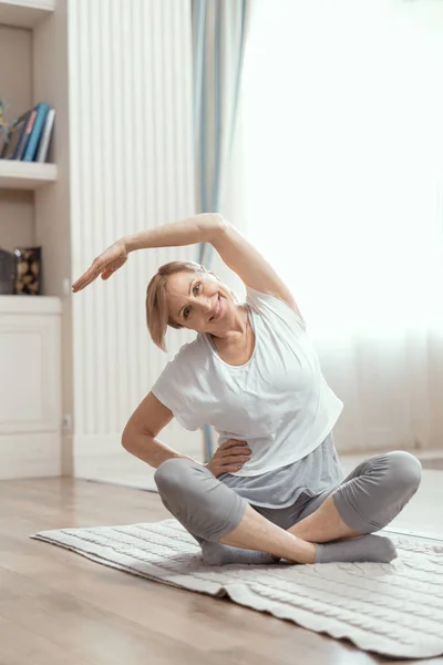 Веселая зрелая женщина делает упражнения йоги — стоковое фото