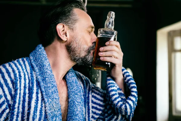 Primer plano de una barba brutal con una botella de su whisky favorito . — Foto de Stock