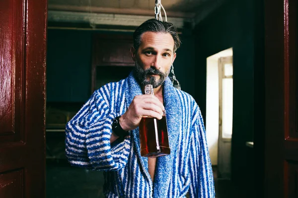 Handsome drunk man holds a bottle of whiskey — Stock Photo, Image