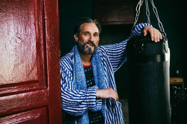 Un hombre de aspecto brutal con una barba fuma un cigarrillo después de tomar una ducha . — Foto de Stock