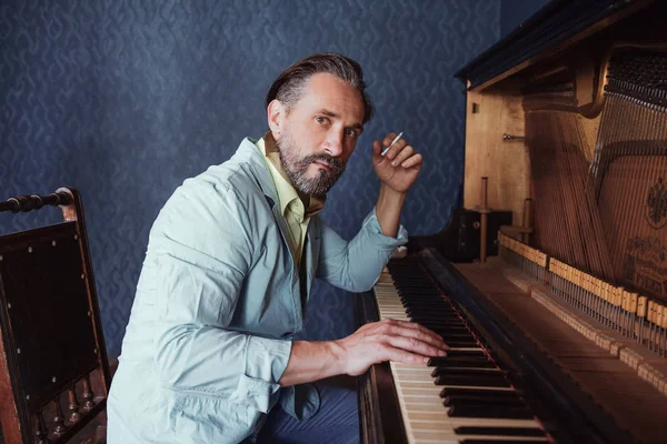 Homem brutal com barba 40 anos toca piano velho . — Fotografia de Stock