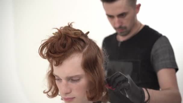 Mester fodrászat csinál haircut egy fiatal fickó, vörös, hosszú hajú. — Stock videók