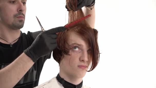 スタイリストの美容師は、赤い髪を持つスタイリッシュな髪型若い男を作ります. — ストック動画