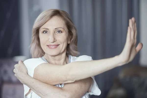 Mulher encantadora está esticando as mãos antes de fazer exercício de ioga — Fotografia de Stock