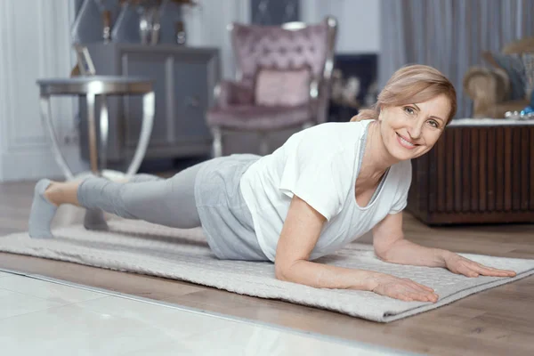 Beautiful mature woman stands in plank position