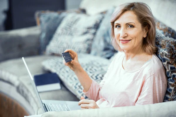 Mujer sonriente sostiene un ordenador portátil que trabaja desde casa — Foto de Stock