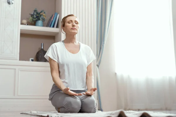 Atrakcyjna dojrzała kobieta uprawia jogę w pokoju Zdjęcie Stockowe
