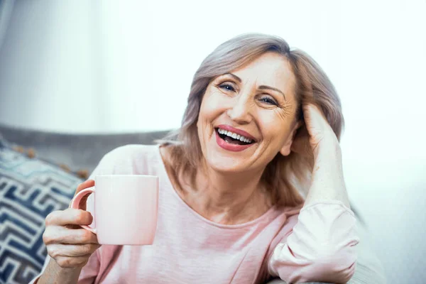 Mujer madura feliz con la taza de tes en sus manos — Foto de Stock