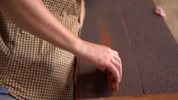 Jovem carpinteiro lixar madeira na oficina — Vídeo de Stock