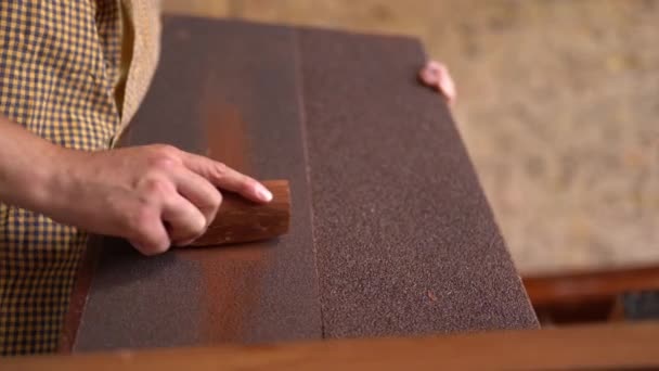 Joven carpintero lijando madera en taller — Vídeos de Stock