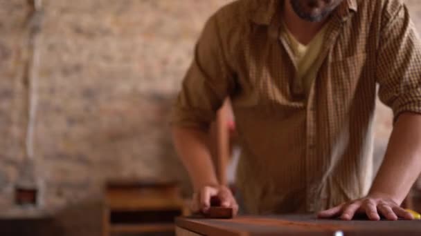 Joven carpintero lijando madera en taller — Vídeos de Stock