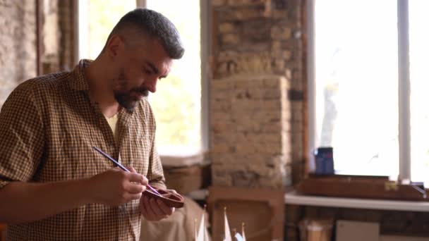 Řemeslník maluje figurky v dílně — Stock video