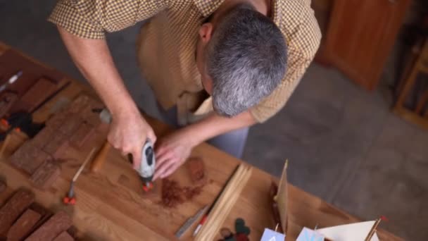 Carpinteiro usa uma ferramenta rotativa de broca o esculpir prancha de madeira — Vídeo de Stock