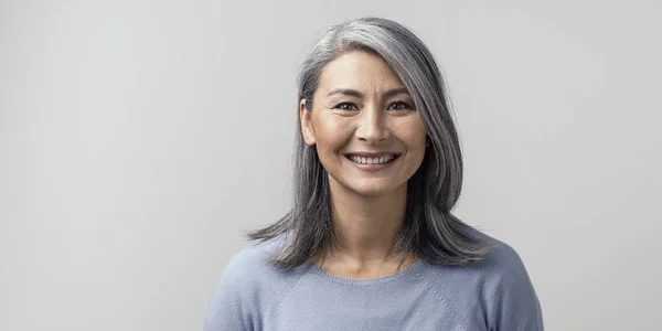 Красива азіатська з сірим волоссям посміхаючись стоїть біля стіни — стокове фото