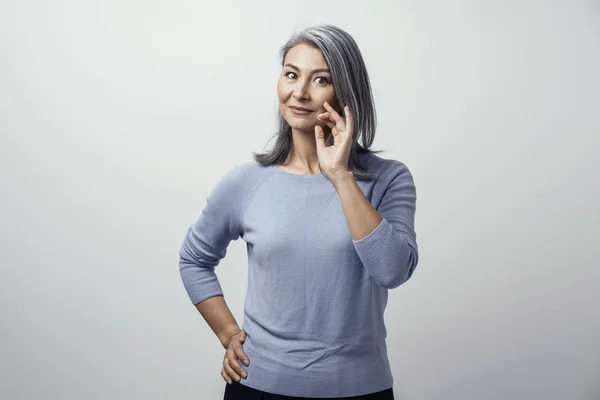 Lächelnde asiatische Frau berührt ihr graues Haar — Stockfoto