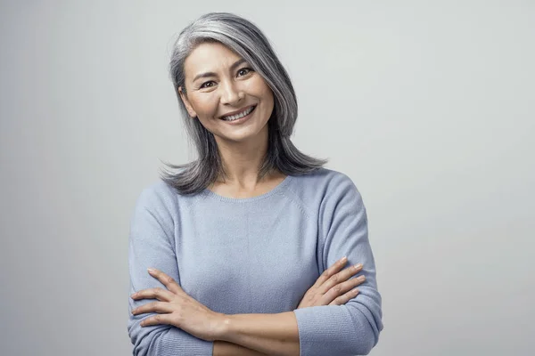 Glimlachend Aziatische senior vrouw met gekruiste armen — Stockfoto