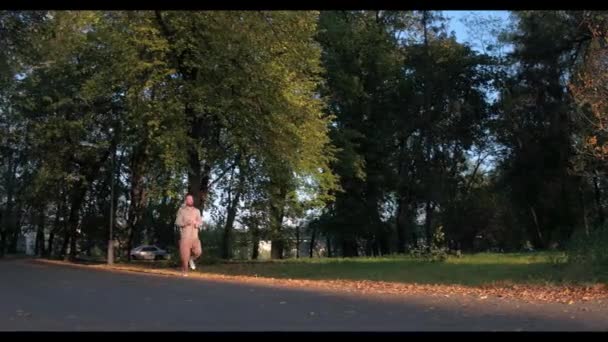 El hombre corre en verde bosque de otoño aligerado con el sol — Vídeos de Stock