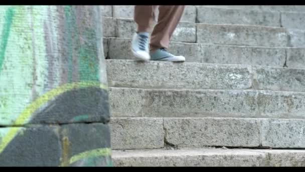 Bonito homem de cabelos escuros usando tênis está nas escadas — Vídeo de Stock