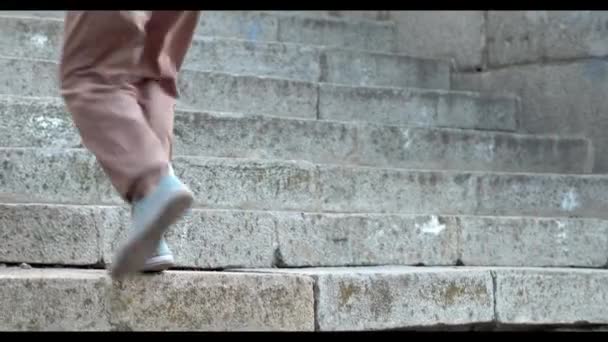 スニーカーを履いたハンサムな黒髪の男が階段にいます — ストック動画