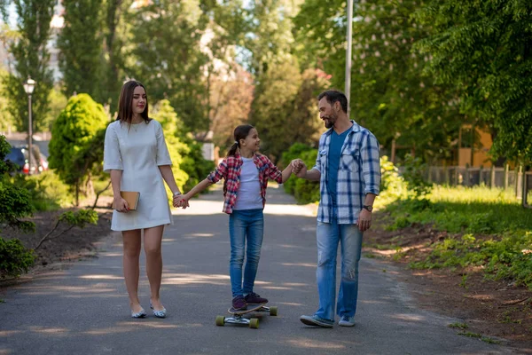Lachende familie met een skateboard in het zomerpark — Stockfoto