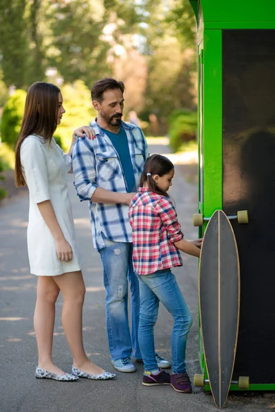 Familj tillbringa tid i parken när du står nära butiken. Skateboard är av butiken. — Stockfoto