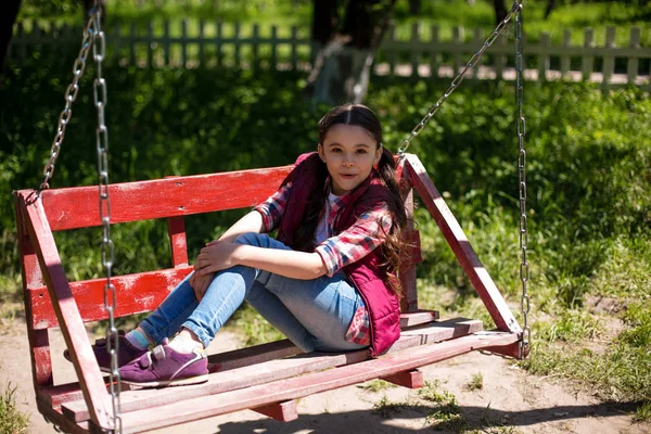 Маленькая девочка сидит на качелях в парке . — стоковое фото