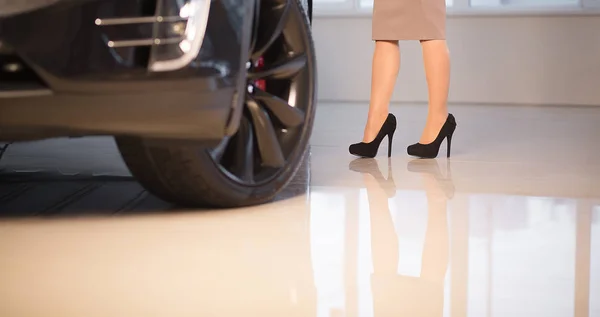 Жінка стоїть поруч з Brand-New Luxury Vehicle в автосалоні. — стокове фото