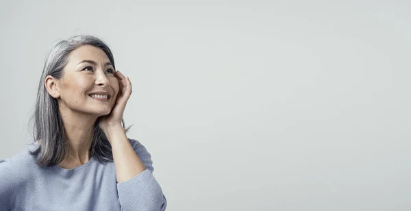 Perfil lateral de la encantadora mujer asiática sonriendo sobre fondo blanco — Foto de Stock