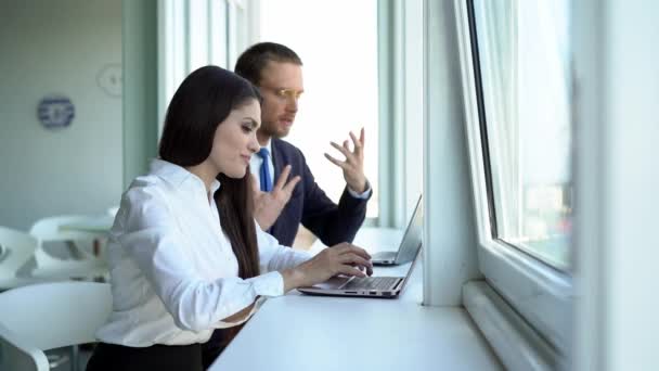 Beautiful Girl y su compañera de trabajo están sentadas en la mesa y trabajando juntas — Vídeos de Stock