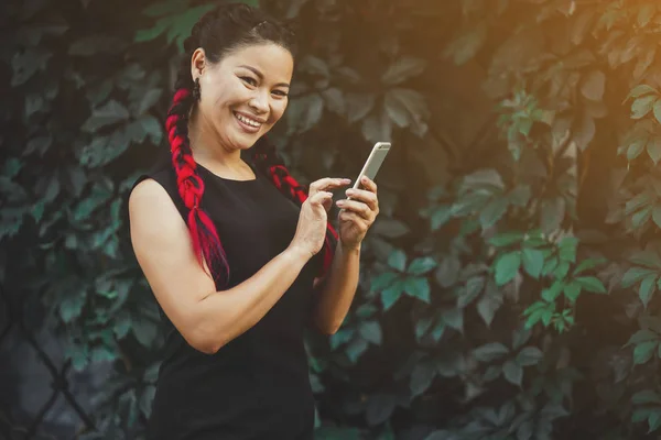 Mooie volwassen Aziatische vrouwelijke model met smartphone outdoor — Stockfoto