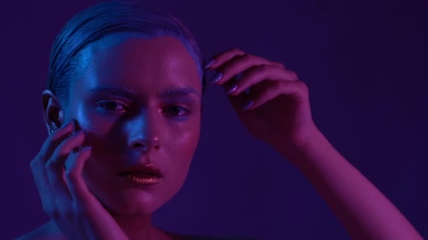 Όμορφο θηλυκό μοντέλο που ποζάρει σε μπλε και ροζ φως νέον στο στούντιο — Αρχείο Βίντεο