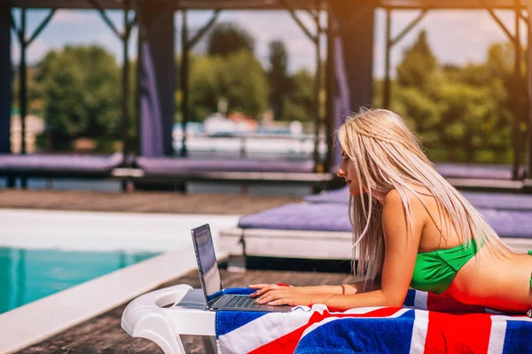 Concentrated Blondie Young Woman Is Laying On The Deck Chair And Typing On Her Laptop Near The Pool. — Stock Photo, Image