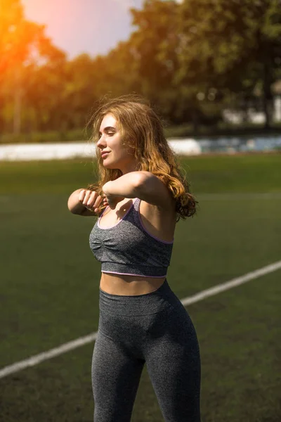Giovane ragazza sportiva con acconciatura riccia sullo stadio estivo — Foto Stock