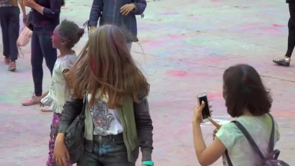 Děti běží vesele po člověku s barvou v náručí — Stock video