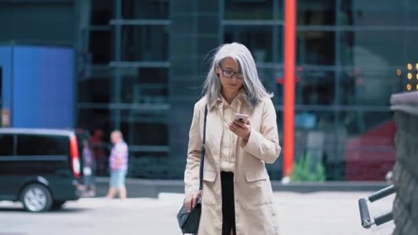 Den medelålders asiatiska kvinnan går nedför gatan — Stockvideo