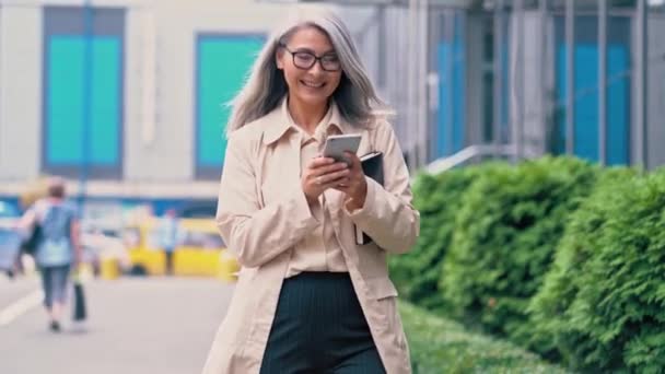 La mujer asiática de mediana edad camina por la calle de la ciudad — Vídeo de stock