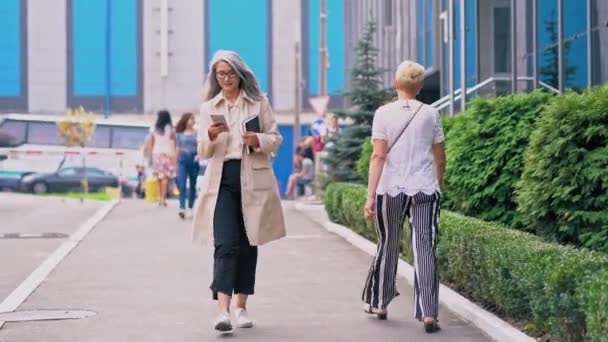 中年のアジア人女性がグリーンストリートを歩いている — ストック動画
