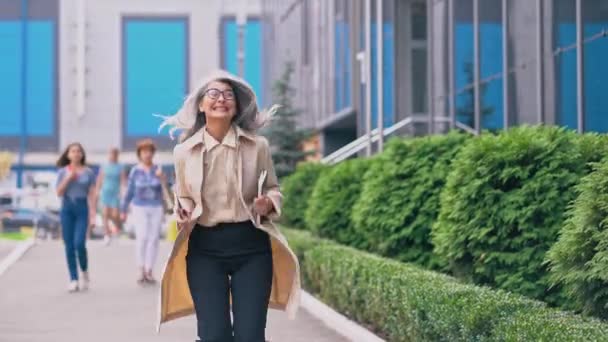 Середнього віку азіатських жінка йде вниз по зеленій вулиці — стокове відео